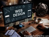 The image shows a desk with a computer monitor in the center. The monitor displays the words "WEB DESIGN" in white text on a...