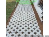The image shows a long, rectangular pathway made of white plastic blocks arranged in a grid-like pattern. The blocks are even...