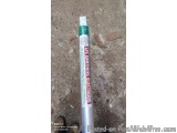 The image shows a cylindrical metal pole with a green handle. The pole is lying on a concrete surface. On the handle, there i...