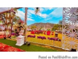 The image shows an outdoor wedding venue with a beautiful view of the mountains in the background. The venue is decorated wit...