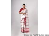 The image shows a woman wearing a traditional Indian saree. The saree is white with red polka dots all over it. The blouse is...