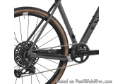 The image is a close-up of the rear wheel of a mountain bike. The bike has a black frame with a brown rim and a black saddle....
