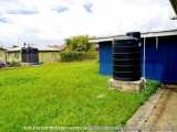The image shows a large black water tank in a grassy area. The tank is cylindrical in shape and appears to be made of metal....