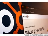 The image is a close-up of a computer screen with the HubSpot logo on the left side. The logo is a black and orange circle wi...