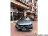 The image shows a black Mercedes-Benz car parked on a brick pavement in front of a building with a red awning. The building a...