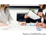 The image shows a man and a woman sitting at a desk in an office, engaged in a conversation. The woman is on the left side of...