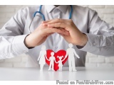 The image shows a person's hands holding a red heart-shaped paper cutout of a family. The person is wearing a white shirt and...