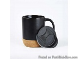 The image shows a black ceramic mug with a cork lid. The mug has a handle on the right side and a round base with a small hol...
