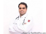 The image is a portrait of a young man wearing a white lab coat with a stethoscope around his neck. He has a red badge on his...