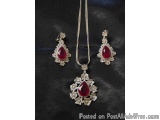 The image shows a necklace and earring set. The necklace is a long silver chain with a pendant in the center. The pendant is...