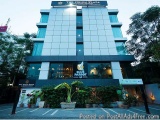 The image shows the exterior of a modern hotel building. The building is a two-story structure with a flat roof and large win...