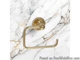 The image shows a gold-colored toilet paper holder on a white marble surface. The holder is made of metal and has a round, cy...