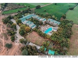 The image is an aerial view of a large, multi-story building with multiple levels and a swimming pool in the center. The buil...