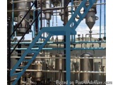 The image shows a large industrial machine with multiple pipes and valves. The machine appears to be made of stainless steel...