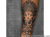 The image is a tattoo of the Hindu deity Ganesha on someone's arm. The tattoo is black and white and is done in a traditional...