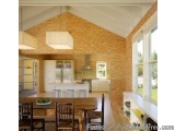 The image shows a modern kitchen and dining area in a house. The kitchen has a wooden ceiling with exposed beams and a large...