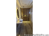 The image shows a modern bathroom with a minimalist design. The floor is made of light-colored tiles, and the walls are paint...