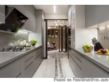 The image shows a modern kitchen with a large island in the center. The island has a gas stove and a sink with a built-in ove...