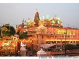 The image shows a large Hindu temple with a golden dome on top. The temple is decorated with colorful lights and has multiple...