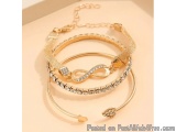 The image shows a stack of three bracelets on a beige background. The bracelets are made of gold metal and have a chain link...
