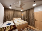 The image shows a bedroom with two single beds. The beds are neatly made with white linens and yellow pillows. There are two...