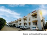 The image shows a row of white buildings with red and yellow accents. The buildings are arranged in a neat and orderly manner...