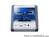 The image shows a Roland MX-50 3D printer. It is a large, rectangular machine with a grey body and a blue control panel on th...