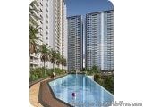 The image shows a modern apartment complex with three tall buildings. The buildings are white and have balconies on the balco...