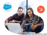 The image shows a young couple sitting on a couch and looking at a laptop. They are both smiling and appear to be engaged in...