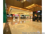 The image shows the interior of a shopping mall. The floor is made of marble tiles and there is a circular pattern in the cen...