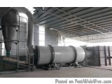 The image shows a large industrial machine inside a warehouse. The machine is made of stainless steel and has a cylindrical s...