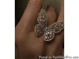 The image shows a close-up of a person's hand with a ring on their ring finger. The ring is in the shape of a butterfly, with...
