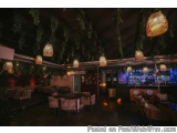 The image shows the interior of a restaurant or bar. The ceiling is covered with hanging lanterns made of bamboo, creating a...