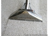 The image shows a close-up of a metal floor scraper. The scraper has a triangular shape with a pointed end and a flat base. I...