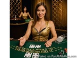 The image shows a young woman sitting at a blackjack table in a casino. She is wearing a gold dress and has long brown hair....