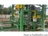 The image shows a large green industrial machine with a yellow crane attached to it. The machine appears to be a concrete blo...