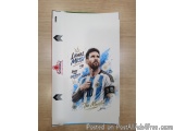 The image is a photograph of Lionel Messi, a professional soccer player for Argentina. He is shown in a blue and white stripe...