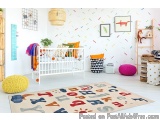 The image shows a child's room with a white crib in the center. The crib is decorated with colorful throw pillows and blanket...