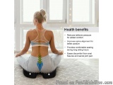 The image shows a woman sitting on a yoga mat in a room with large windows. She is wearing a blue sports bra and grey legging...