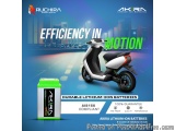 The image is an advertisement for Ruchira Green Earth's Akira Lithium-ion batteries. The background of the image is a citysca...