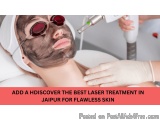 The image shows a woman lying on a white surface with a black facial mask on her face. She is wearing a white headband and re...