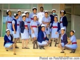 The image shows a group of young women dressed in blue uniforms and white caps, posing for a group photo on a set of stairs....