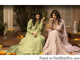 The image shows two young women sitting on a stone bench in a garden. They are both wearing traditional Indian attire, with o...