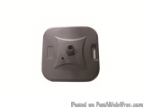 The image shows a small, square-shaped object with a dark grey color. It appears to be made of plastic or a similar material...