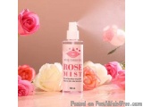 The image shows a bottle of rose mist spray on a pink background. The bottle is white with a pink label that reads "wing cosm...