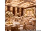 The image shows a luxurious and elegant banquet hall with high ceilings and chandeliers. The room is decorated with white and...