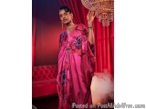 The image shows a woman standing in a room with red curtains and a chandelier hanging from the ceiling. She is wearing a long...