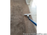 The image shows a close-up of a carpet cleaning machine. The machine has a blue handle and a silver body. The body of the mac...