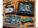 The image shows a desk with various electronic components scattered on it. On the left side of the image, there is a black ha...