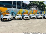 The image shows a group of white cars parked in a parking lot. There are six cars in total, all of which appear to be new mod...